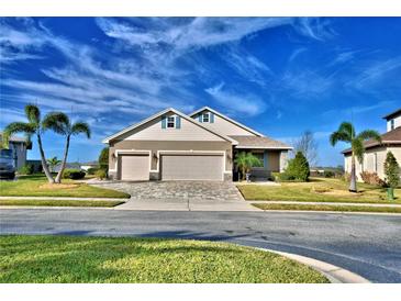 Tan house with three-car garage and landscaped yard at 537 Pond Cypress Ct, Auburndale, FL 33823