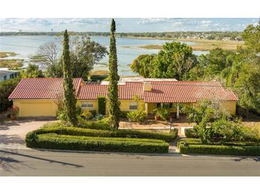 Lakefront home featuring a red tile roof and lush landscaping, offering serene views and curb appeal at 1121 Sunset Dr, Lake Wales, FL 33853