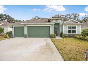 Two-story house with a green exterior, three-car garage, and landscaped lawn at 3033 Adrian Dr, Ormond Beach, FL 32174