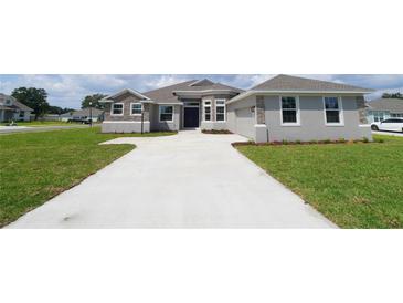 Charming single-Gathering home with stone accents, light gray paint, attached garage, and a large front yard at 304 Denna Ln, Auburndale, FL 33823