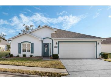 White house with teal accents, two-car garage, and landscaped lawn at 524 Lake Suzanne Dr, Lake Wales, FL 33859