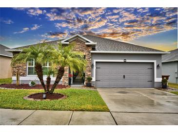 Single-story home with gray siding, stone accents, and a two-car garage at 918 Revere Ave, Haines City, FL 33844