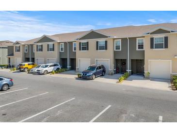 Row of townhomes featuring neutral color schemes, garage, and convenient parking at 1157 Blue Jay Dr, Davenport, FL 33837