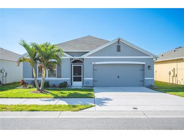 Charming single-story home boasts a well-manicured lawn, a two-car garage, and a delightful palm tree at 144 Emanuelle Dr, Winter Haven, FL 33884