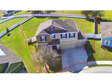 Two-story tan home with blue shutters, neutral colored siding, a well-manicured lawn, and an attached two-car garage at 1510 Shorewood Dr, Auburndale, FL 33823