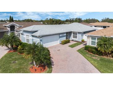 Well-maintained home featuring a brick driveway, lush landscaping, and a charming exterior design at 3418 Raleigh Dr, Winter Haven, FL 33884