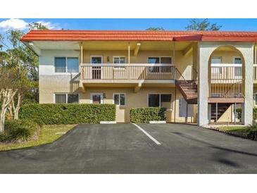 Two story condo building featuring red tile roof and well maintained landscaping at 400 El Camino Dr # 101, Winter Haven, FL 33884