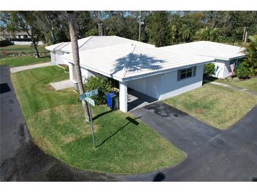 Aerial shot featuring homes with white tile roofs and carports, surrounded by lush landscaping and green lawns in a neighborhood setting at 720 Fonda Ct # 54, Lakeland, FL 33803