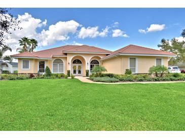 Charming single-story home featuring a red tile roof, manicured lawn, and arched entryway at 105 Wyndham Dr, Winter Haven, FL 33884