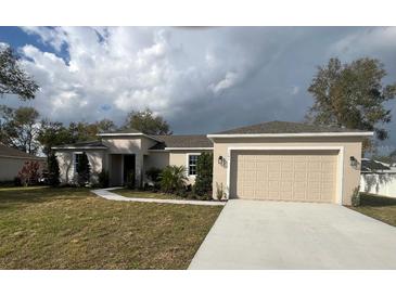 Attractive single-story home featuring a two-car garage, neutral stucco, well-maintained lawn, and simple landscaping at 1205 Lake Loop Rd, Winter Haven, FL 33880