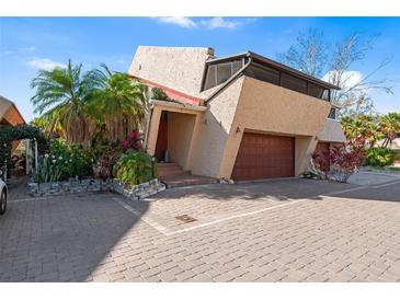 Unique home exterior with a two-car garage, brick driveway, stucco walls and tropical landscaping at 15 Casarena Ct, Winter Haven, FL 33881