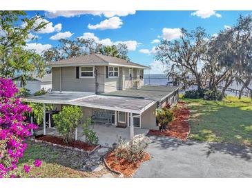 Inviting waterfront home featuring a covered patio, lush landscaping, and serene water views at 3943 Chambers St, Lake Wales, FL 33898