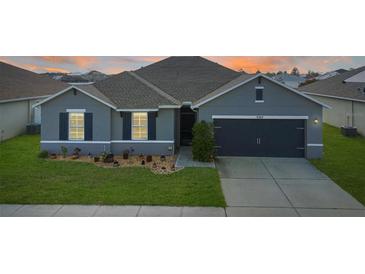 Charming single-story home featuring a well-manicured lawn and a two-car garage at 5767 Lakeside Landings Blvd, Winter Haven, FL 33881