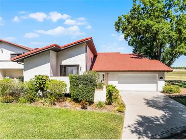 Charming home featuring a red tile roof, well-manicured lawn, and a two-car garage at 7016 Village Dr, Lake Wales, FL 33898