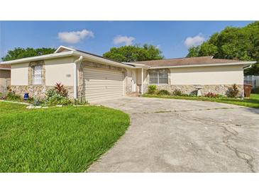 Charming single-story home featuring a stone facade, attached garage, and well-maintained lawn at 2434 Mill Run Blvd, Kissimmee, FL 34744