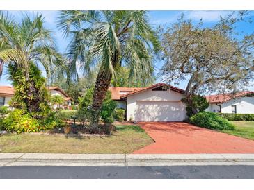 Charming home featuring mature landscaping, an attached garage, and a vibrant, red-toned driveway at 2637 Sunburst Ct, Lake Wales, FL 33898