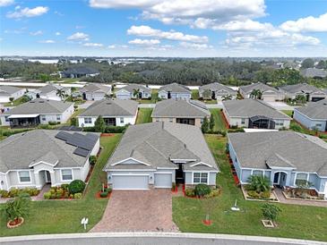Expansive aerial view of a neighborhood showcasing well-maintained homes and landscaping, with a lake in the distance at 3711 Plymouth Dr, Winter Haven, FL 33884