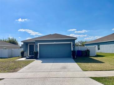 Inviting single-story home with a two-car garage, well-manicured lawn, and beautiful blue siding at 663 Lucerne Blvd, Winter Haven, FL 33881