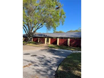 Charming home exterior featuring a well-maintained red fence, lush tree, and inviting walkway at 683 Broadmoor Cir # 683, Winter Haven, FL 33884