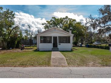 Quaint, one-story home featuring a traditional facade, screen front porch, and a walkway leading to the entrance at 750 Avenue O Sw, Winter Haven, FL 33880