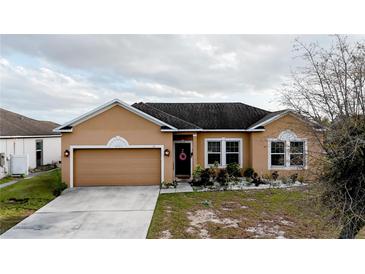 Charming single-story home featuring a well-maintained lawn and a two-car garage at 318 Gladesdale St, Haines City, FL 33844