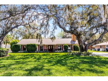 Charming single-story home with a brick chimney, well-manicured landscaping, and mature trees in the front yard at 3614 Twisted Oak Ct, Lake Wales, FL 33898