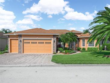 Charming single-story home featuring a three-car garage, lush landscaping, and a paver driveway at 5268 Pebble Beach Blvd, Winter Haven, FL 33884