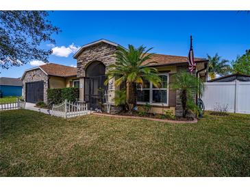 Charming single-story home featuring stone accents, a screened entrance, a well-manicured lawn, and mature palm trees at 625 Hatchwood Dr, Haines City, FL 33844