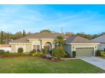 Charming single-story home with well-manicured lawn, lush landscaping, and a welcoming, covered entryway at 7327 Bent Grass Dr, Winter Haven, FL 33884