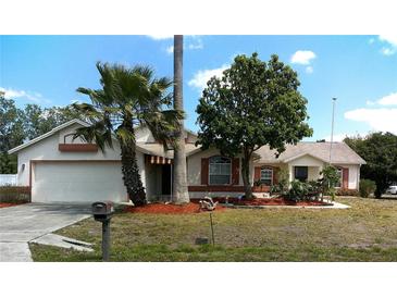 Charming single-story home featuring an attached garage, well-maintained lawn, and mature landscaping, creating curb appeal at 100 Heatherwood Blvd, Lake Wales, FL 33859