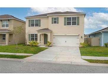 Charming two-story home featuring a well-manicured lawn, neutral stucco, attached garage and colorful green shutters at 2005 Carnostie Rd, Winter Haven, FL 33884