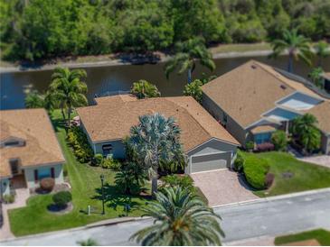 Charming single-story home with a brown roof, a brick driveway, mature landscaping, and waterfront views at 4168 Aberdeen Ln, Lake Wales, FL 33859