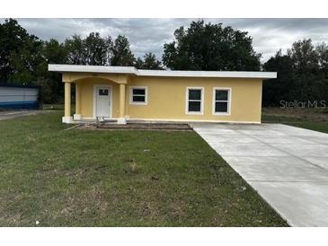 Charming single-story home with a sunny yellow exterior and a spacious concrete driveway at 708 E Broadway St, Fort Meade, FL 33841