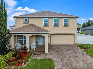 Two-story home with brick driveway, attached two car garage, covered porch and landscaped flowerbeds at 10234 Lenox St, Clermont, FL 34711