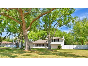 Charming two-story home with mature trees, white siding, and a well-manicured lawn in a serene setting at 151 Lake Ring Dr, Winter Haven, FL 33884