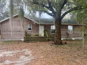 Exterior view of a single story home with wood siding and front yard with tree at 261 Acacia Walk, Lake Wales, FL 33898