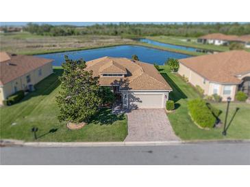 Beautiful single-story home with a brick driveway, attached garage, and serene water views at 3014 Ashton Palms Dr, Lake Wales, FL 33859