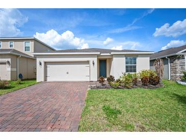 Charming single-story home featuring a two-car garage, blue front door, brick driveway, and well-maintained landscaping at 336 Summer Squall Rd, Davenport, FL 33837