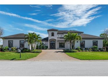 Elegant home featuring a symmetrical design, manicured landscaping, and a brick driveway with a welcoming entrance at 4717 Emerald Palms Ct, Winter Haven, FL 33884