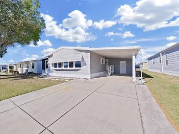 Charming single-story home features a carport, mature tree, and well-maintained front lawn at 4986 Foxwood Lake Dr, Lakeland, FL 33810