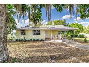 Charming yellow home featuring a metal roof and cozy front porch perfect for relaxing outdoors at 819 Seminole Rd, Babson Park, FL 33827