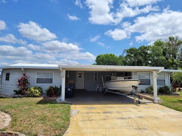 Charming home with a boat parked in the carport, under a bright blue sky at 121 Bonnie Dr, Auburndale, FL 33823