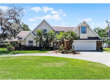 Charming two-story home featuring a spacious front yard, palm trees, and an attached two-car garage at 2 Bridgewater Dr, Winter Haven, FL 33884