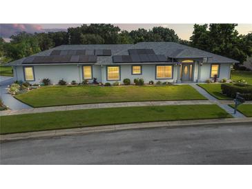 Well-maintained one-story home featuring a lush green lawn, tidy landscaping, and solar panels on the roof at 217 Kent Ct, Haines City, FL 33844