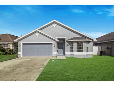 Charming one-story home boasts a well-maintained lawn and a two car garage with a gray exterior paint at 4099 Island Lakes Dr, Winter Haven, FL 33881