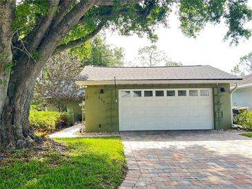 A single-car garage with a brick driveway, green siding, and white garage door is featured in this exterior shot at 579 Saint Andrews Rd, Winter Haven, FL 33884