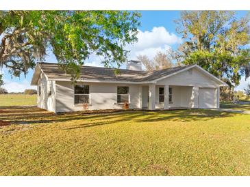 Charming single-story home with a white exterior, well-manicured lawn, and classic architectural details at 6430 Russo Rd, Bartow, FL 33830
