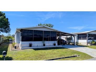 Charming home featuring a screened porch, carport, well-maintained lawn, and tasteful landscaping at 6450 Hollyberry Ne Ln, Winter Haven, FL 33881