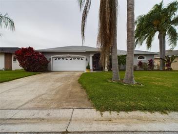 Charming single-story home featuring a well-manicured lawn, mature landscaping, and an attached two-car garage at 7726 Ashford Dr, Lakeland, FL 33810