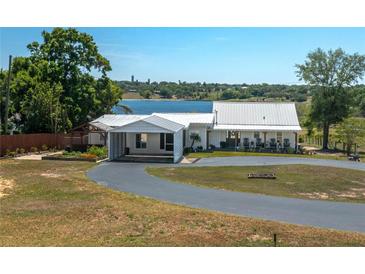 Charming home with a metal roof, circular driveway, and a view of the lake at 100 Masterpiece Rd, Lake Wales, FL 33898